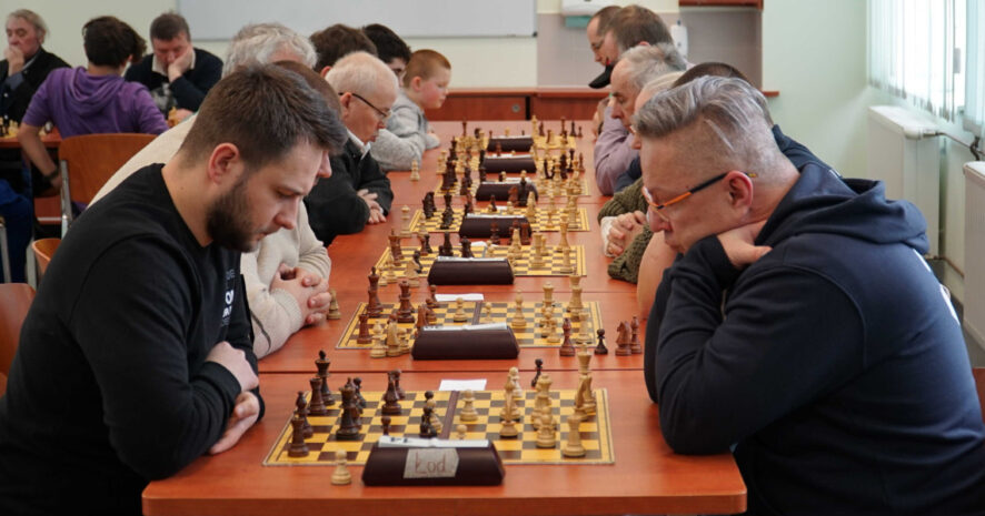 mężczyźni zastanawiają się nad kolejnym ruchem przy szachownicy.